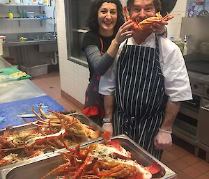 A woman holds a crayfish in front of a chef.
