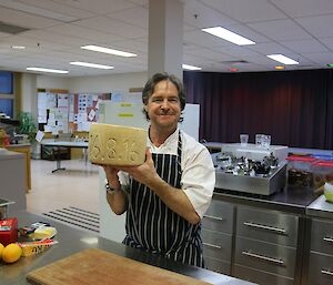 A chef holds a round of cheese.