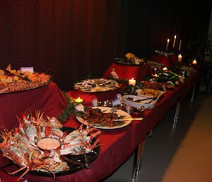 A long table is covered in platters of food and candlelight.