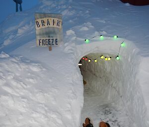 An entrance to a tunnel with party lights and a sign that says “brain Freeze”