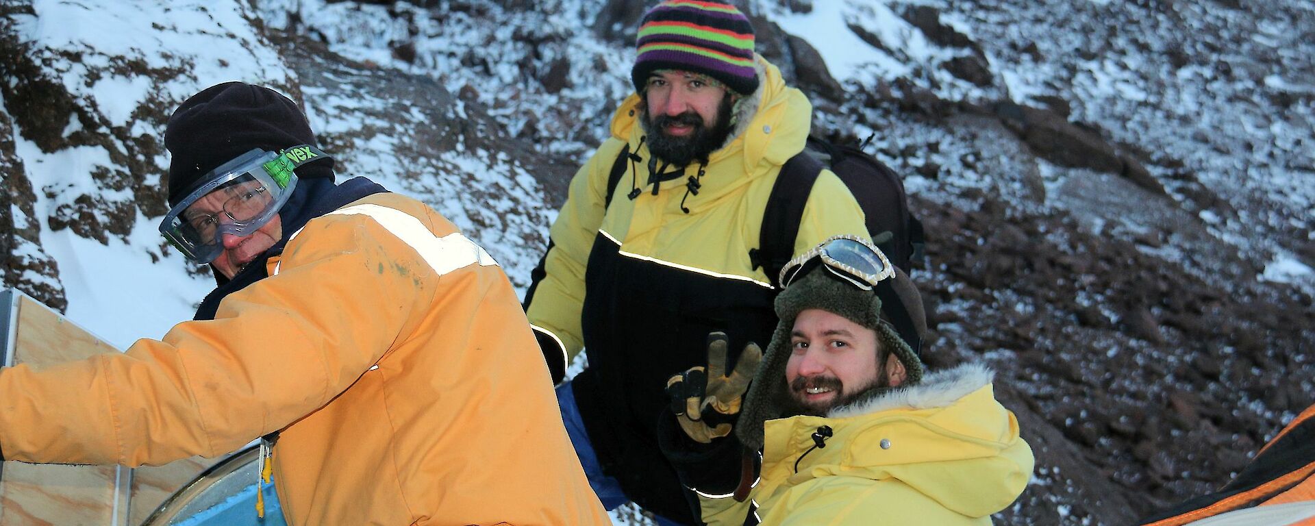 Three men in yellow freezer suits check out the radio repeater.