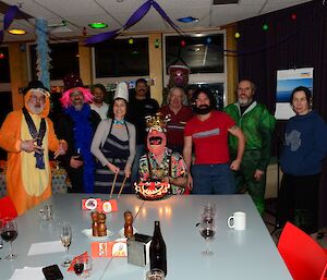 A group of people in fancy dress stand in front of a cake