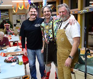 Three men stand arm in arm.