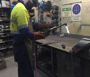 A man wearing safety gear holds an oxy blow torch