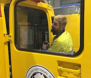 A man fixes a yellow Hägglunds vehicle.