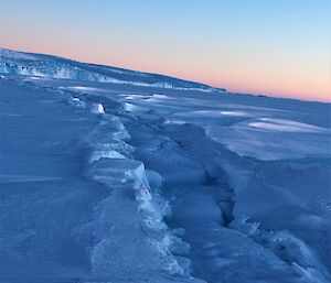 A large tide crack with a pink sky.