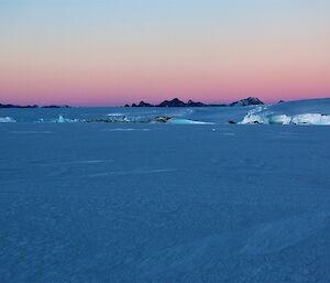 A pink sky behind a mountain range in the background