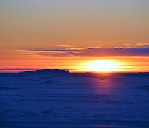 An orange glowing sunset across the sea ice.