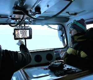 A man and a woman sit is a Hägglunds vehicle using a GPS