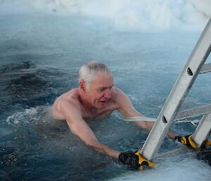 A man with white hair ascends a ladder from an ice pool