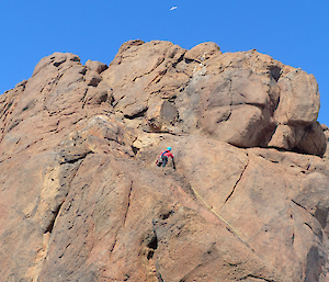 A woman ascends a rocky mountain top.