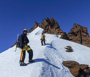 Two men descend a mountain on snow.