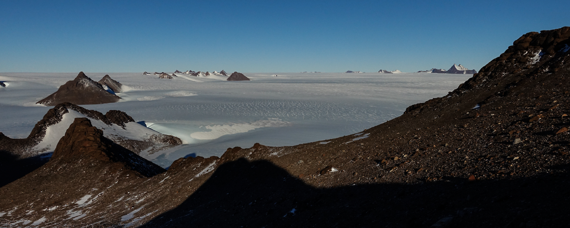 A panoramic shot of mountain peaks above an icy plateau