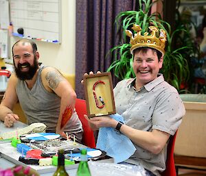 A man at the table with a crown on his head celebrating his birthday.