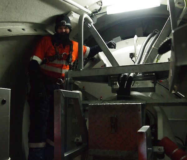 A man in a balaclava stands inside a wind turbine.