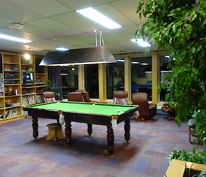 A pool table and armchairs with music area.