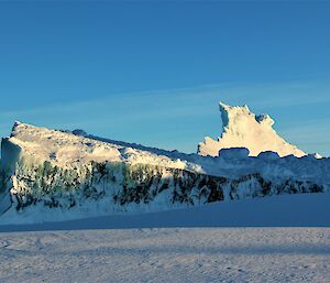 A slab of jade berg in front of an iceberg peak.