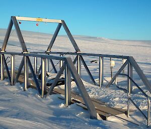 A metal framed pontoon above an icy plateau.