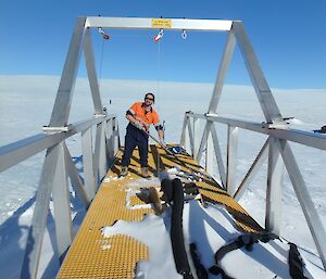 A man in high visibility with a shovel on top of a metal framed pontoon