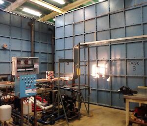 Two large blue metal tanks in a tank house.