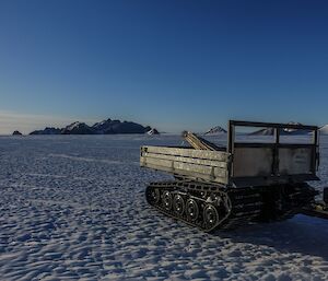 A trailer with canes on icy plateau with mountains in background