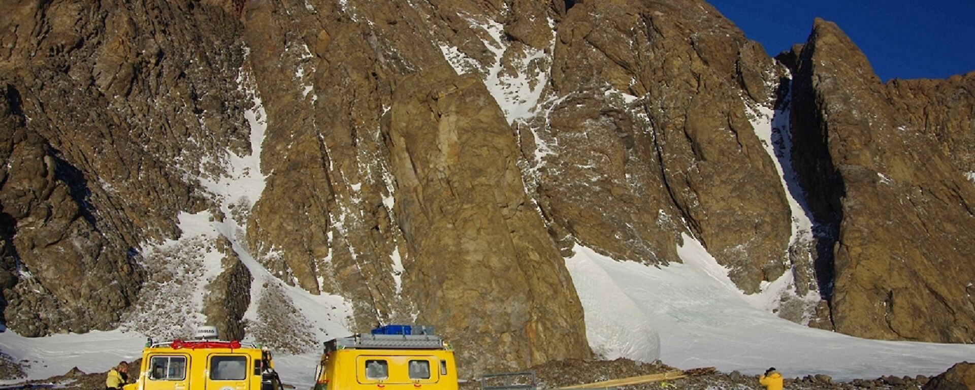 A yellow Hägg in front of mountains towing a trailer full of canes