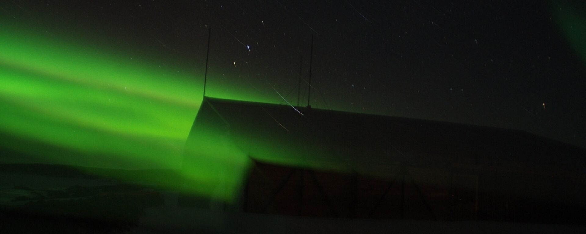 A green aurora shines into a building on station.