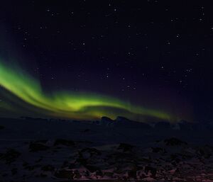 A green and violet spirals over sea ice and icebergs.