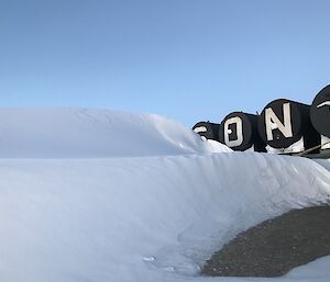 An embankment of snow is built up next to a row of fuel tanks.