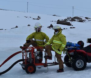 Two men stand next to a mobile water pump.