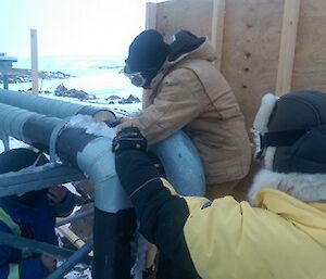 Three men work on a pump outside.