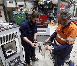 Two men are heating up materials in a workshop.