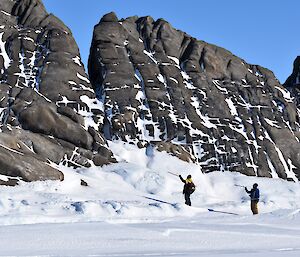 Two men stand at the base of an island pointing in the direction of their route.