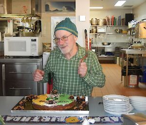 A man in a green shirt and green beanie cuts a cake