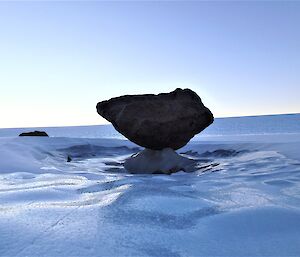 A boulder is suspended in the frozen ice of the plateau