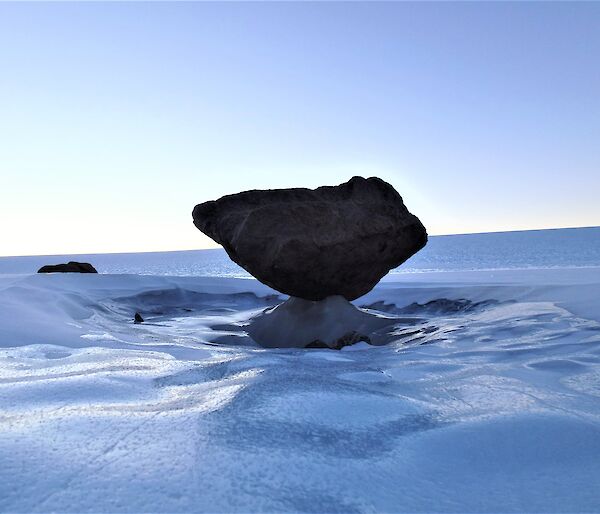A boulder is suspended in the frozen ice of the plateau
