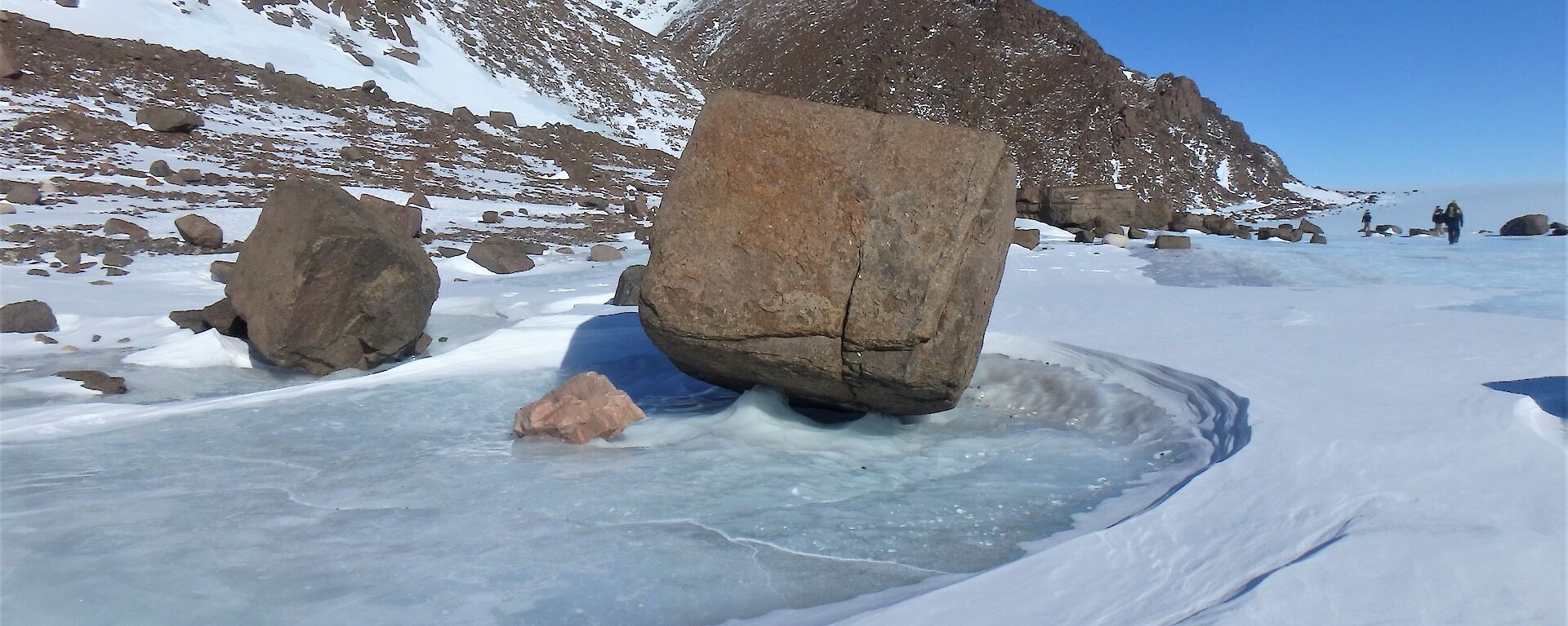 A boulder is frozen in a pool of ice on a plateau.