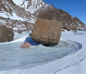 A boulder is frozen in a pool of ice on a plateau.
