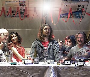 A group of people sit at a long table facing the camera