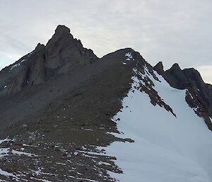 Four men stand on a saddle of a mountain range overlooking a plateau.