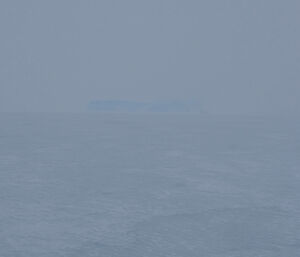 An iceberg on the horizon is obscured by a white out.