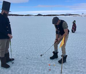 A man putts the golf ball on sea ice.