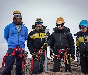 Four people stand on a mountain.