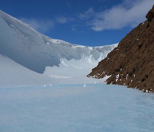 A wind scour next to a rocky mountain.