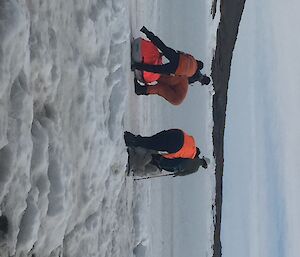 Five people push sleds across sea ice.