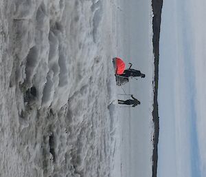 Two people drag sleds over the sea ice.