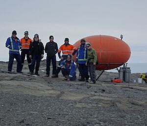 A group of people stand in front of a googie hut on Bechervaise Island