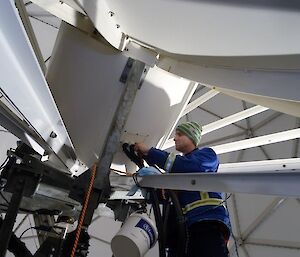 A man working on the back of a satellite dish to remove the attentuator