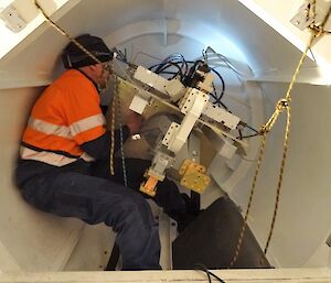 A man working in a tight space to make connections in the back of a satellite dish
