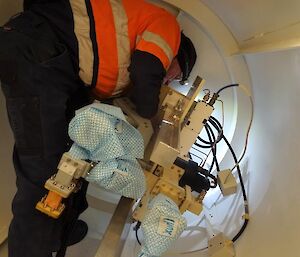 A man working in a tight spot at the back of a satellite dish